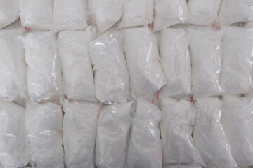 A large number of transparent sachets filled with white powder. White powder packaged in small sachets.