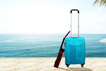 Blue suitcase with a guitar on the beach
