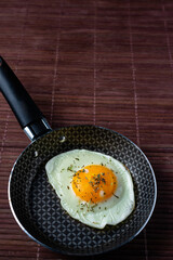 Frying pan with fried egg on a bamboo table
