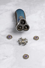 An old electric razor with a disassembled trimmer head on a marble background