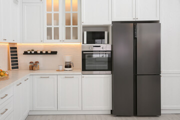 Light kitchen interior with stylish furniture and modern equipment