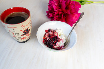 cottage cheese with strawberry, cup of coffee and pink peony on white table