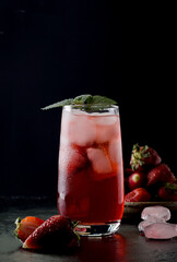 Strawberry cocktail in a high glass. Cold summer drink with ice in a low key.