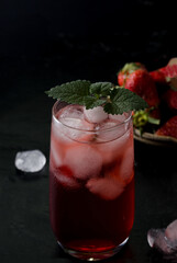 Cocktail with red ice in a high glass glass in a dark key
