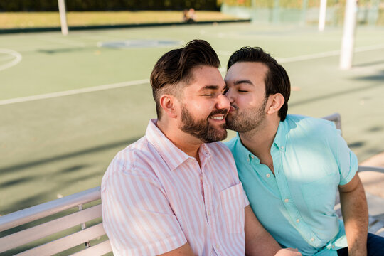 Adorable Man Closes His Eyes While His Boyfriend Gives Him a Loving Kiss on the Cheek