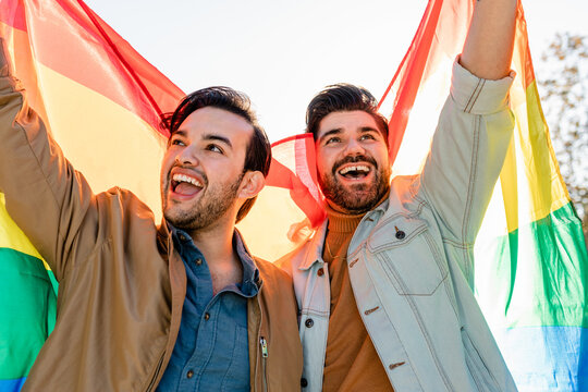 Happy Gay Couple Proudly Marches With Pride Flag at Pride Parade