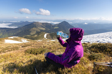 Woman hiker enjoying high peak view on mountains in summer. She is drinking water. Pip Ivan peak....