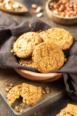 Healthy homemade oatmeal cookies with peanuts in a wooden bowl on a brown kitchen table closeup