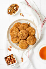 Healthy homemade oatmeal cookies with peanuts in a white plate on the light gray kitchen table top view