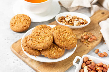 Healthy homemade oatmeal cookies with peanuts in a white plate on a light gray kitchen table closeup