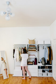 Unrecognizable woman choosing clothes in wardrobe