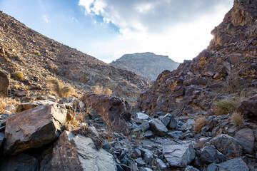 Stony, dry riverbed (wadi) with remains of raw ore of copper, green stones and rocks, Copper Hike...