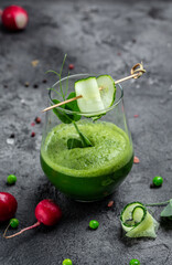 Refreshing kale cucumber green smoothie in a glass on concrete background. Detox smoothie, green fresh peas, cucumber, radish, spinach and lime. vertical image. top view