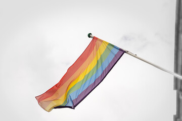 Pride Flag flying on a pole in the wind, symbol of equality for people from the LGBTQ background