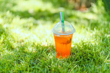 Refreshing drink of lemon and lime lemonade transparent glass on a green grass a hot day