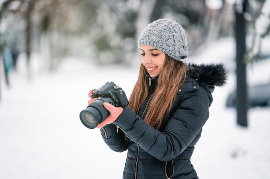 Woman using photo camera in park in winter