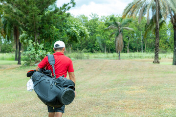 Fototapeta premium Athletes walk carrying a golf club bag on the field.