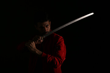 A man in red jacket with katana sword in shadows