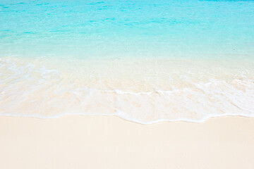 Clean fine sand beach, white foam and blue-green water in Maldives