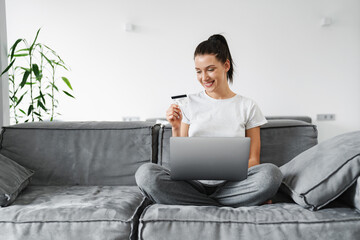 Smiling happy young woman in casual wear using laptop