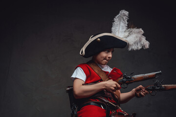 Fototapeta premium Little pirate aiming pistols against dark background
