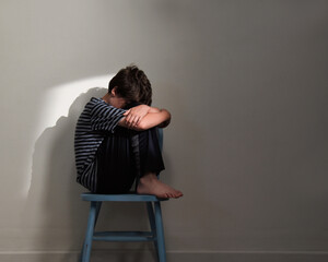 Sad Child Sitting in Room on Chair