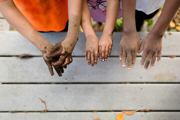 Multiracial siblings hold out muddy hands