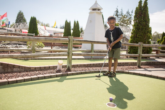 Boy sinks putt at minigolf