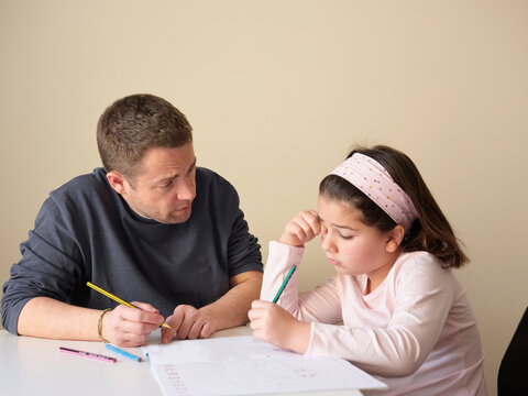 Little girl studying with father at home
