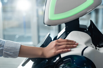 cropped view of female hand touching robot in office