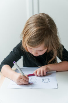 young preschool girl learns writing while focusing hard