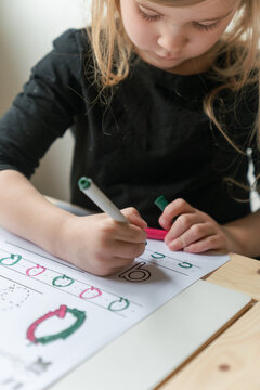 young preschool girl practices writing - detail