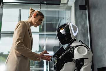 young businesswoman operating robot in office