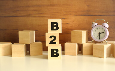 Three wooden cubes stacked vertically on a brown background make up the word B2B.