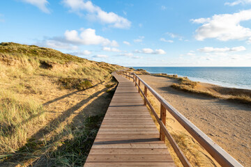 Fototapeta na wymiar Wooden boardwalk along the North Sea coast near Kampen, Sylt, Schleswig-Holstein