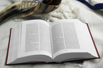 Tallit, shofar and open Torah on white marble table, closeup. Rosh Hashanah celebration