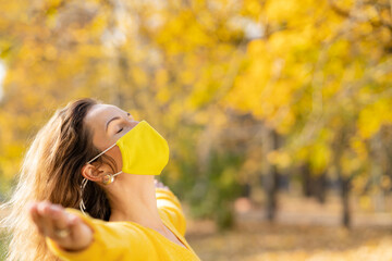 Happy woman wearing protective mask in autumn park