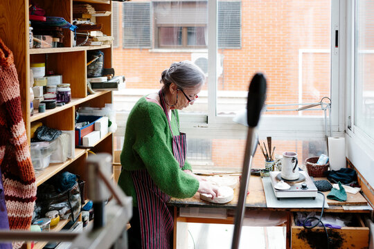 Grey-haired woman working with a plaster mould in her sculptor workshop
