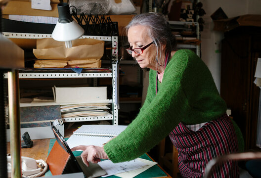 Elderly woman using electronic device in her workshop