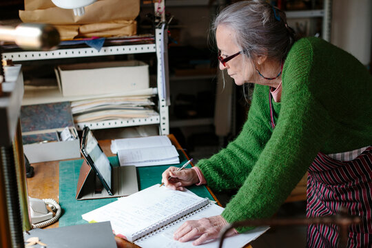 Elderly artisan woman checking a device in her workshop