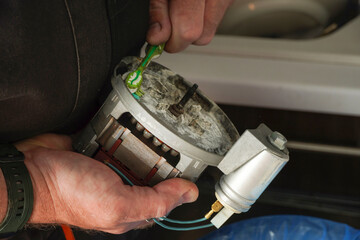     Repair Service Worker. Repairman is removing scale on the pomp of old dishwasher machine....