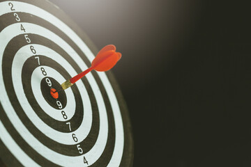 Red dart arrow hitting in the target center of dartboard