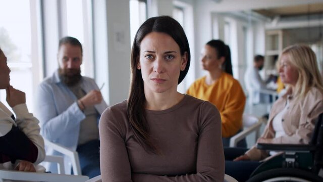 Group of people on therapy session, depressed woman looking at camera.