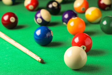 Many colorful billiard balls and cue on green table