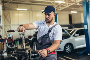 Technician working on checking and service car in workshop garage; technician repair and maintenance engine of automobile in car service