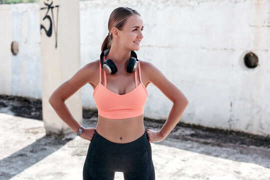 Happy sportive woman with headphones standing on street