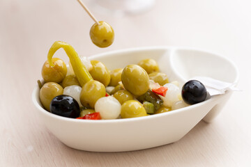 wooden stick prodding vegetarian or vegan snac made up of olives, chilli, chives, and pepper. healthy snac concept. Mediterranean diet. Spain