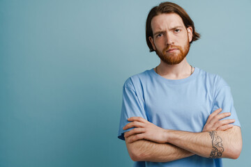 Young ginger man with beard frowning and looking at camera