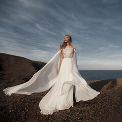 Fototapeta na wymiar Fashion bride in beautiful wedding dress near the sea