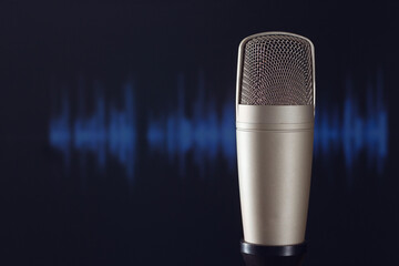Studio microphone in front of the recording screen showing waveform